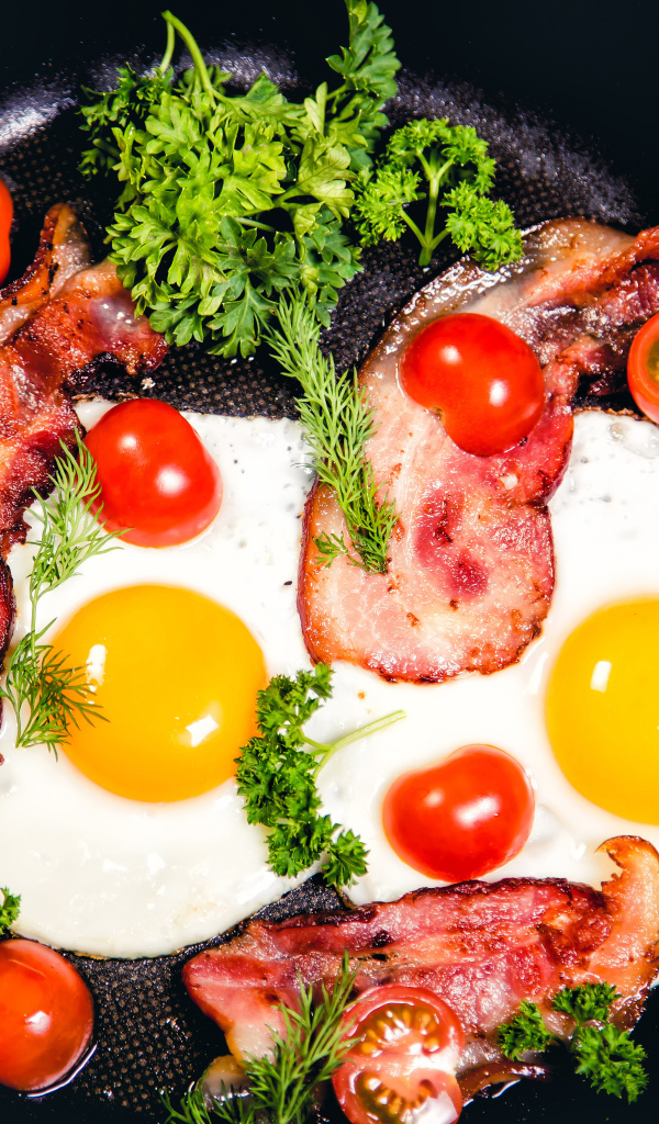 Яичница с беконом, помидорами и зеленью в сковороде на завтрак