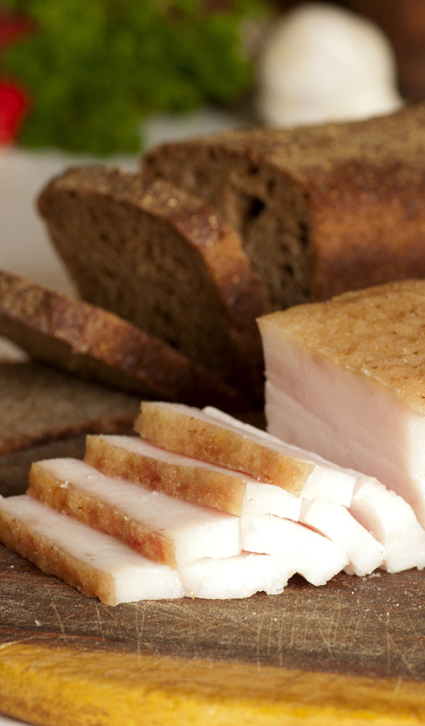 Нарезанное кусочками сало и черный хлеб на разделочной доске