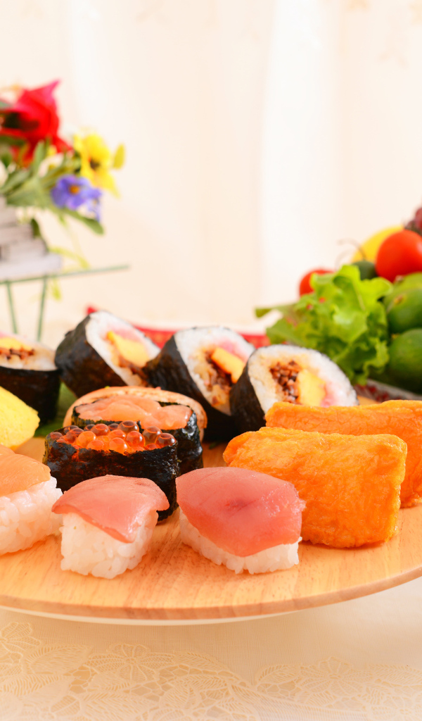 Суши на столе с фруктами и салатом из овощей