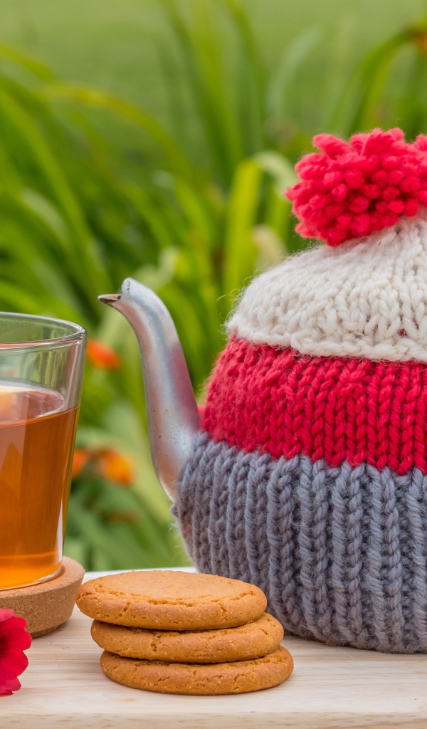 Чайник с чашкой чая на столе с печеньем и цветами