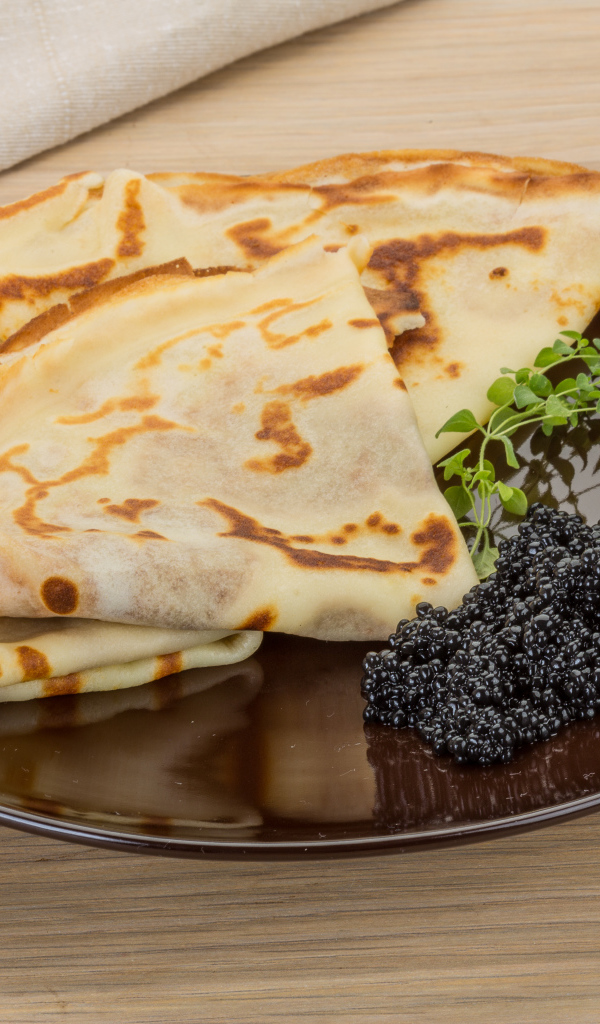 Тонкие блины на тарелке с черной икрой