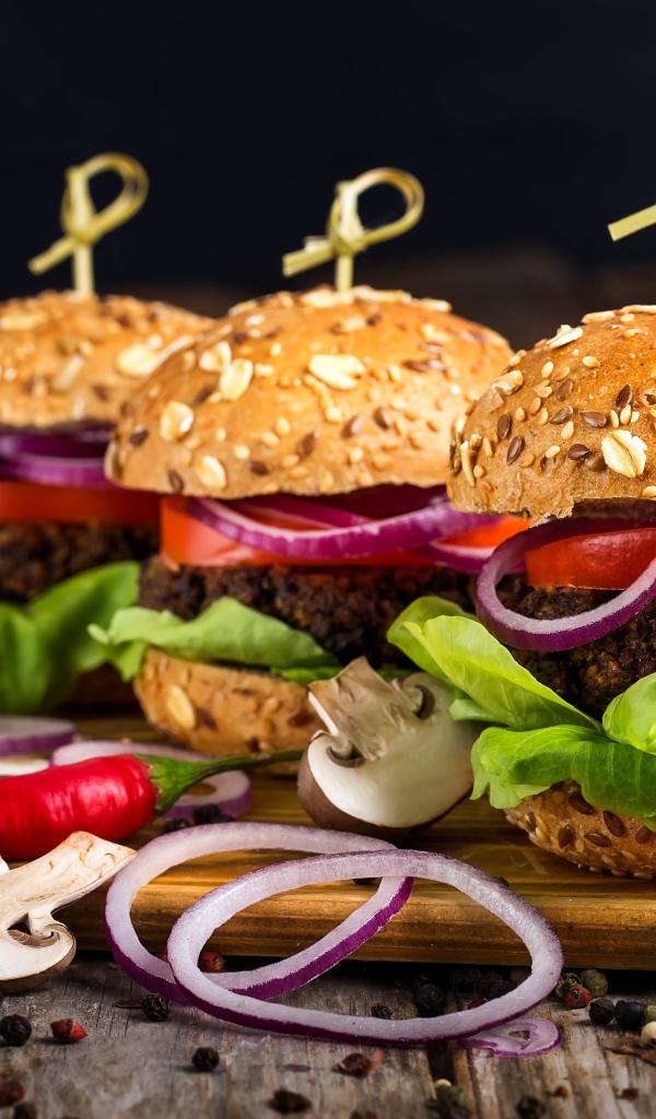 Три аппетитных гамбургера с кольцами лука и перцем