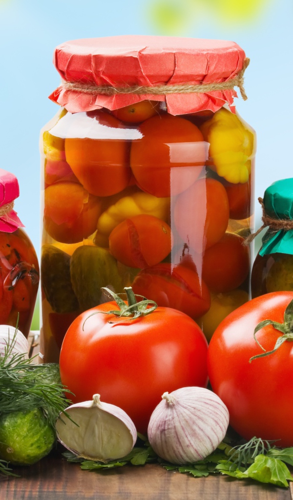 Три банки с заготовками из огурцов, помидоров и сладкого перца