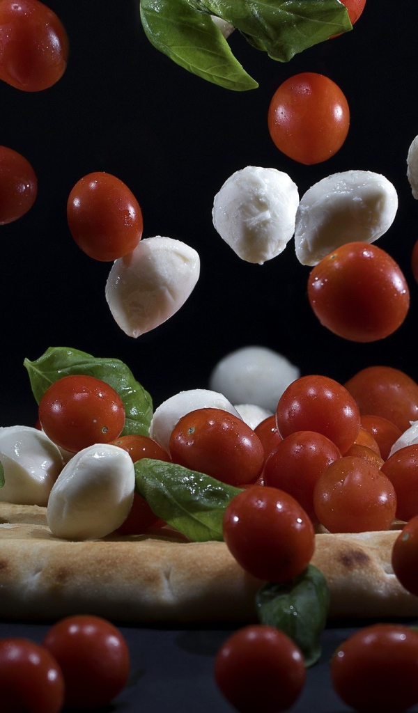 Помидоры и сыр Моцарелла падают на пиццу 