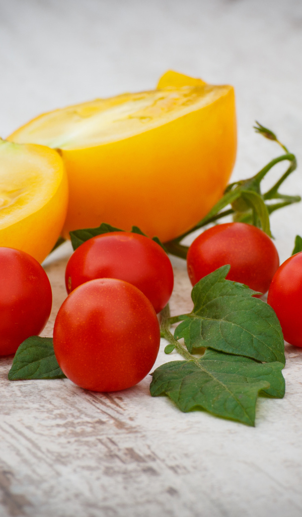 Желтые и красные помидоры на деревянной доске