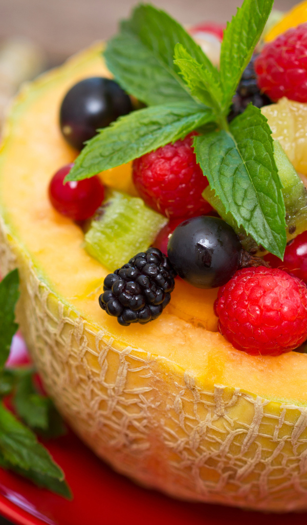 Аппетитные свежие ягоды с листьями мяты в половине дыни