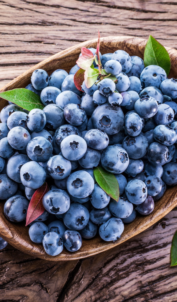 Ягоды свежей черники в тарелке на деревянном столе