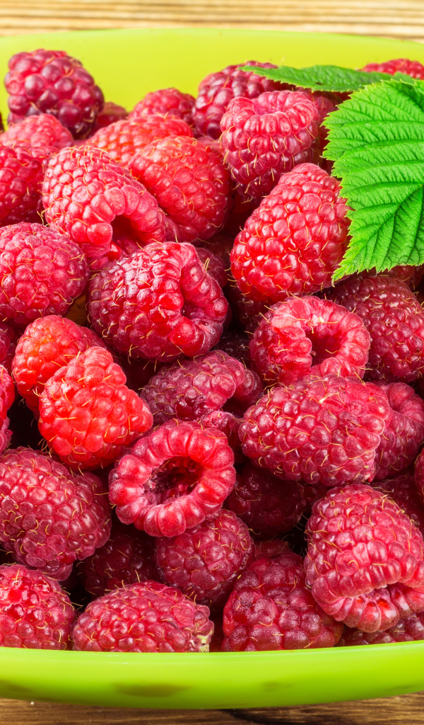 Свежая малина в зеленой миске на столе