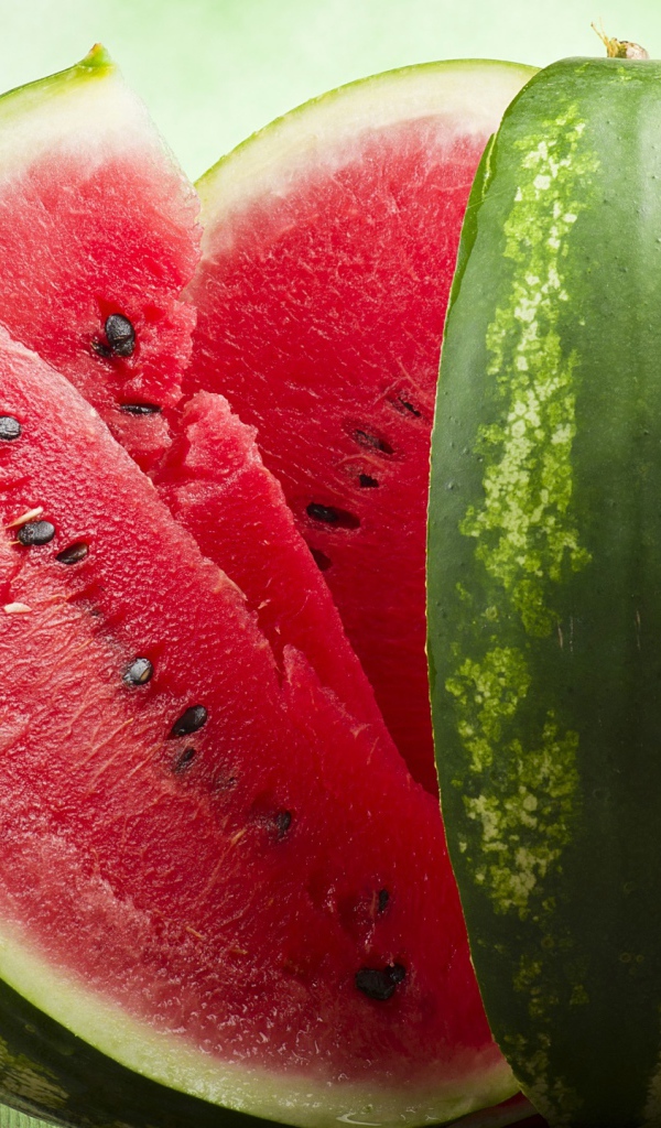 Большой спелый арбуз нарезанный скибками  на столе