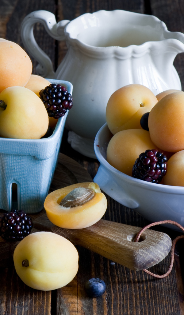 Спелые абрикосы и ягоды на столе 