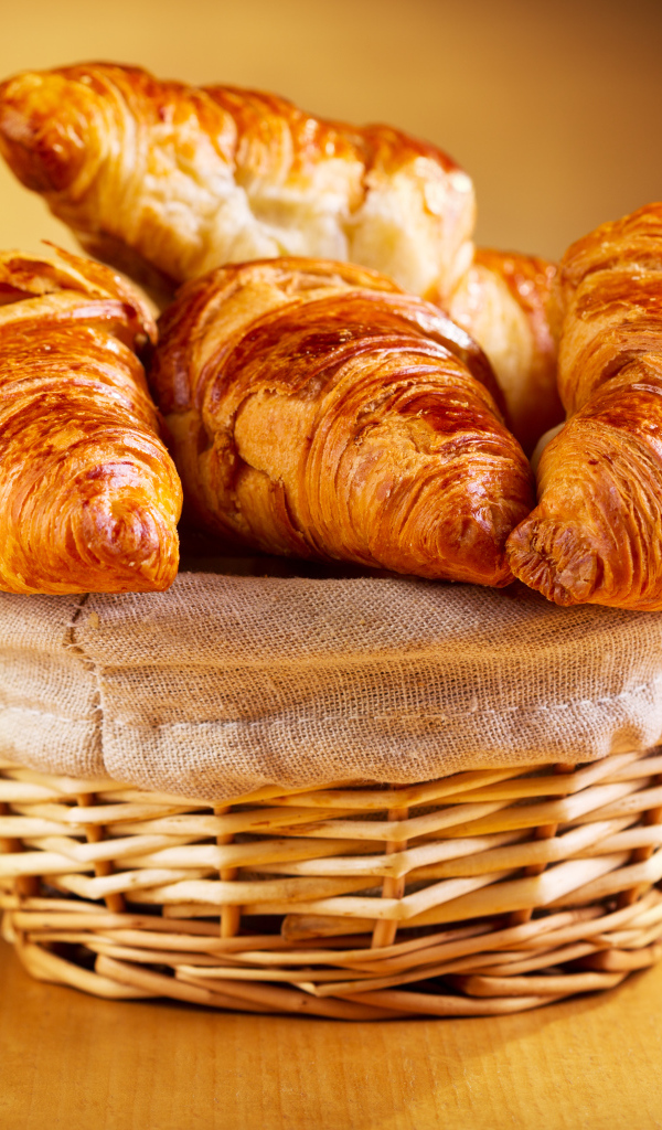 Корзина со свежими круассанами на столе