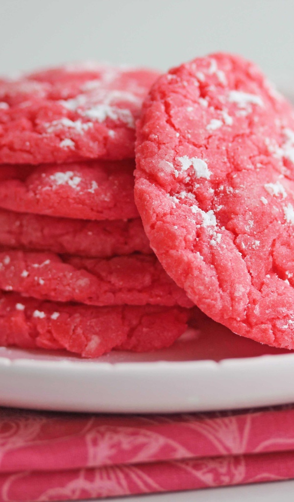 Печенье розового цвета на белой тарелке с сахарной пудрой