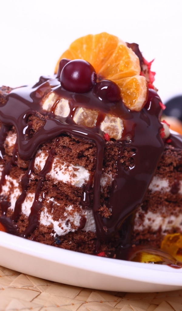 Аппетитное пирожное с шоколадной глазурью, трубочками и мандаринами