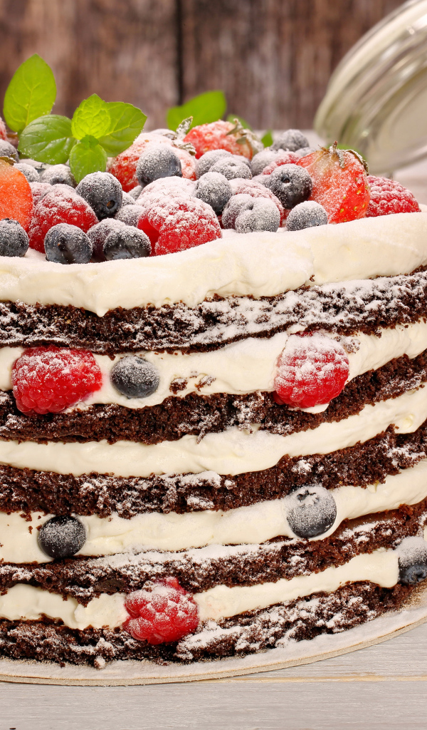Аппетитный торт с кремом и ягодами посыпан сахарной пудрой