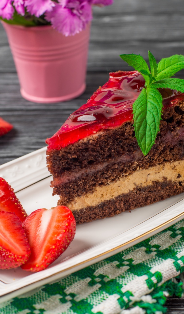 Аппетитный кусок торта на тарелке с ягодами клубники