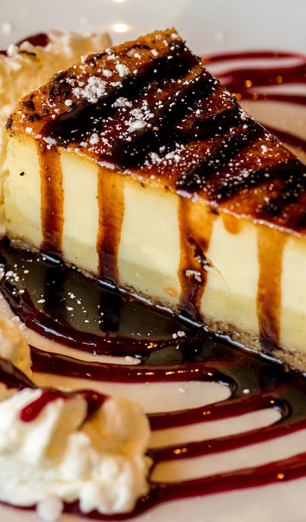 Аппетитный кусок чизкейка со сливками и клубничным джемом