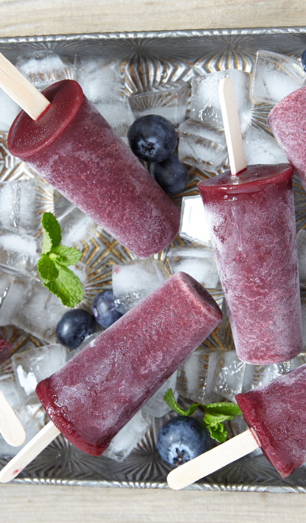 Вкусное черничное мороженое на палочке в лотке со льдом