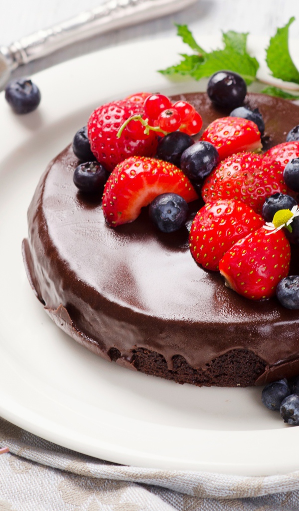 Вкусный торт в шоколаде с ягодами свежей клубники и черники