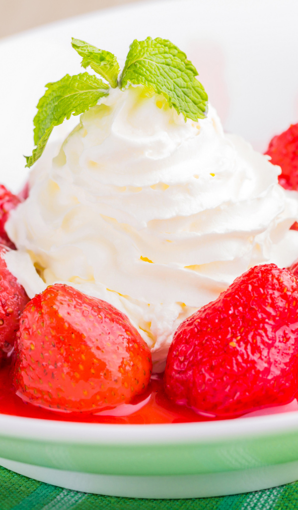 Вкусные сливки с клубникой на белой тарелке