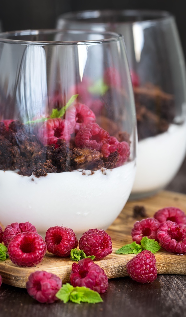 Десерт со сливками, шоколадом и свежей малиной в стеклянных стаканах