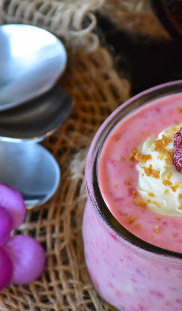 Десерт с малиной и кремом на столе с ложками