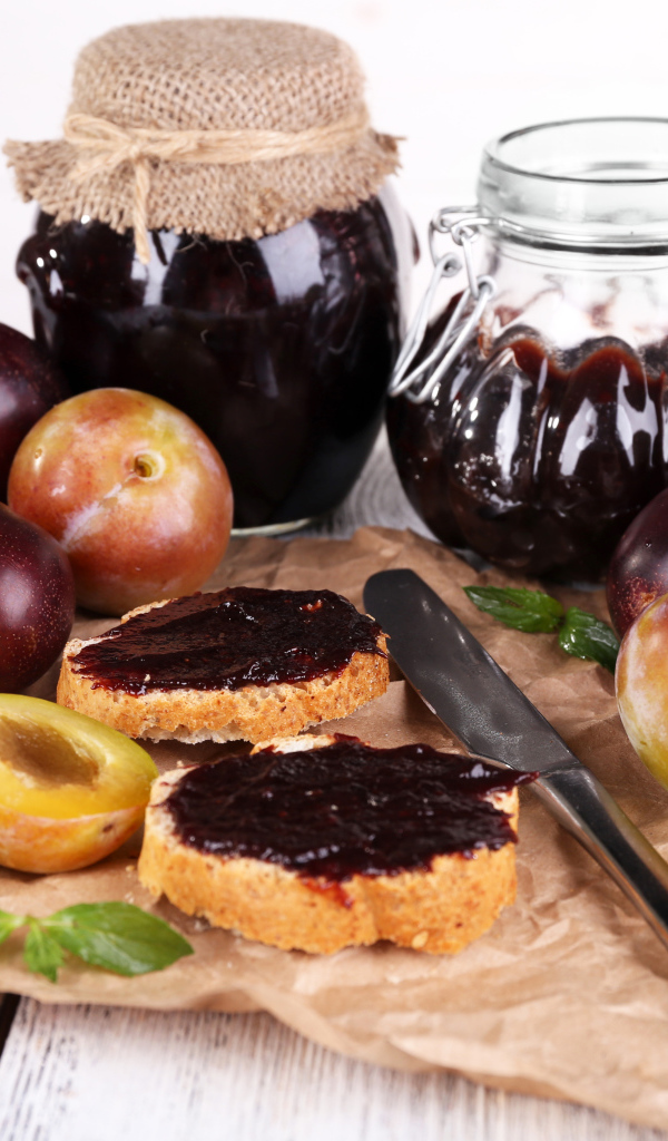 Свежие сливы и сливовый джем на столе 