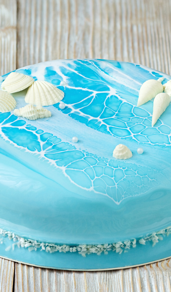 Глянцевый торт голубого цвета украшен сахарными ракушками
