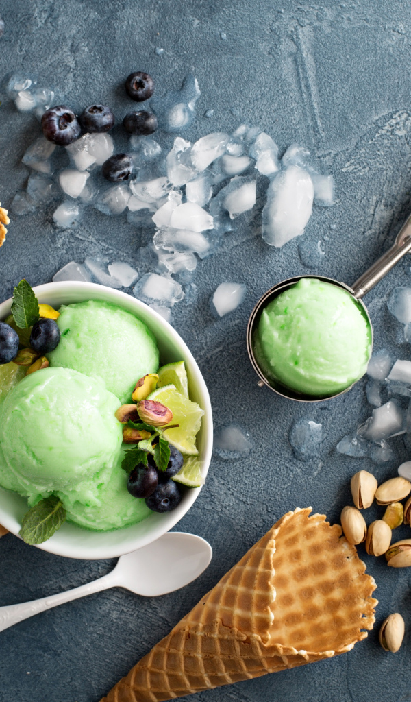 Мороженое с лаймом и фисташками на столе с вафельными рожками и льдом