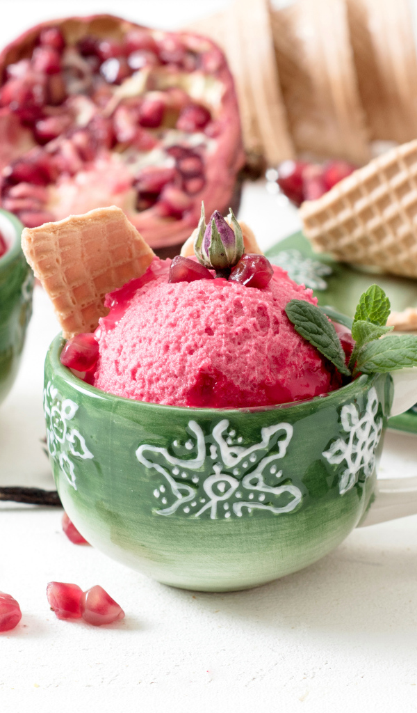 Мороженое с зернами граната в зеленых чашках на столе