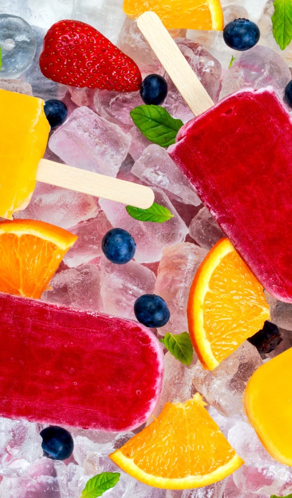 Разноцветное фруктовое мороженое с ягодами лежит на кусочках льда