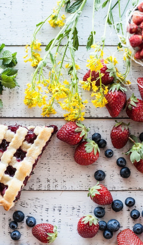 Кусочки пирога на столе с ягодами клубники и черники