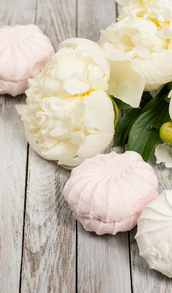 Сладкий зефир на столе с белыми пионами