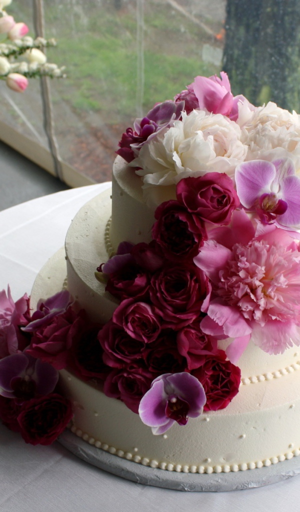 Большой свадебный торт украшен живыми цветами