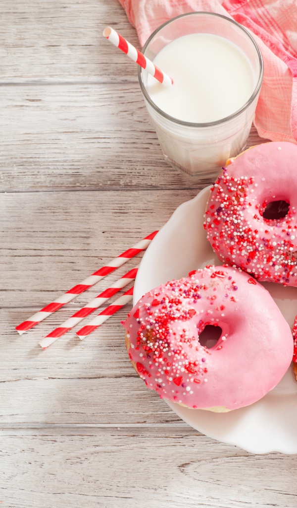 Три аппетитных пончика с розовой сахарной слазурью и стаканом молока