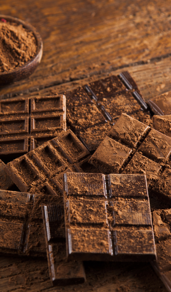 Плитки черного шоколада на столе с какао бобами