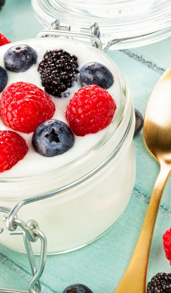 Йогурт со свежими ягодами малины, черники и ежевики в стеклянной банке на завтрак