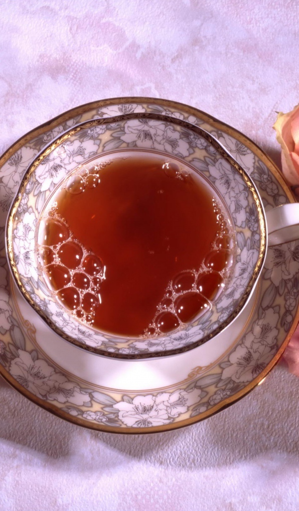 Красивая чашка черного чая на столе с розовыми розами