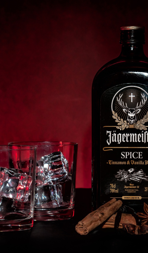 Бутылка ликера Jägermeister на столе с корицей и стаканами