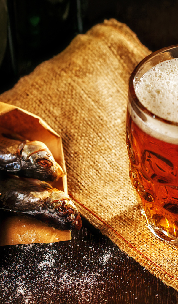 Бокал пива с сушеной рыбой на столе
