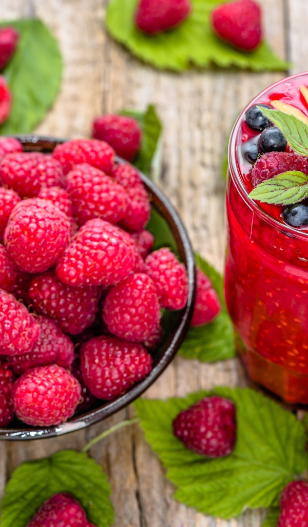 Стакан ягодного смузи на столе со свежими ягодами малины