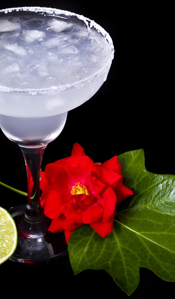 Бокал коктейля со льдом и лаймом на черном фоне