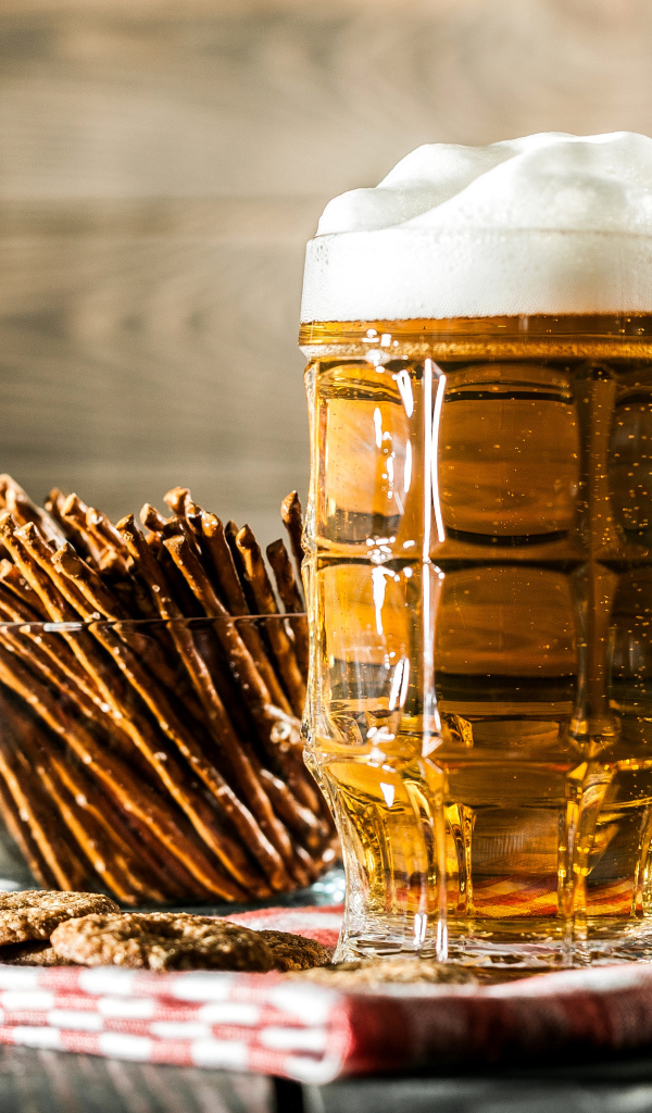 Бокал свежего пива с выпечкой на столе