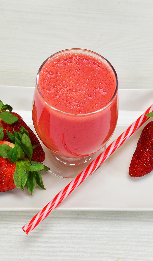 Бокал клубничного коктейля со свежей клубникой и трубочкой