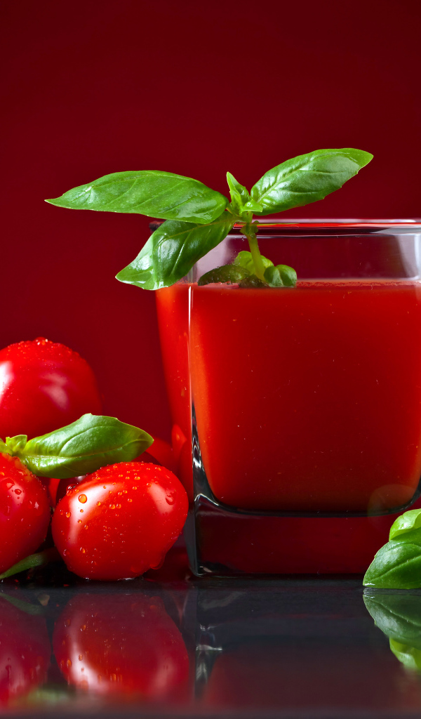 Стакан томатного сока со свежими помидорами на столе