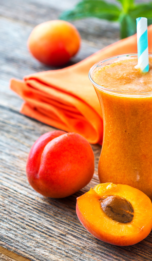 Абрикосовый смузи в стакане на столе со свежими ягодами
