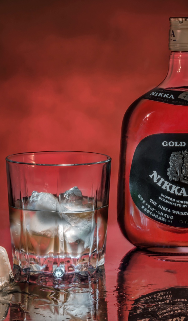 Бутылка Nikka Whisky на столе со стаканом со льдом