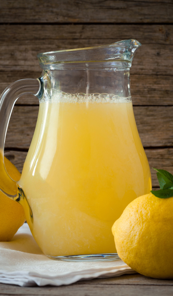 Свежевыжатый лимонад в стеклянном кувшине на столе