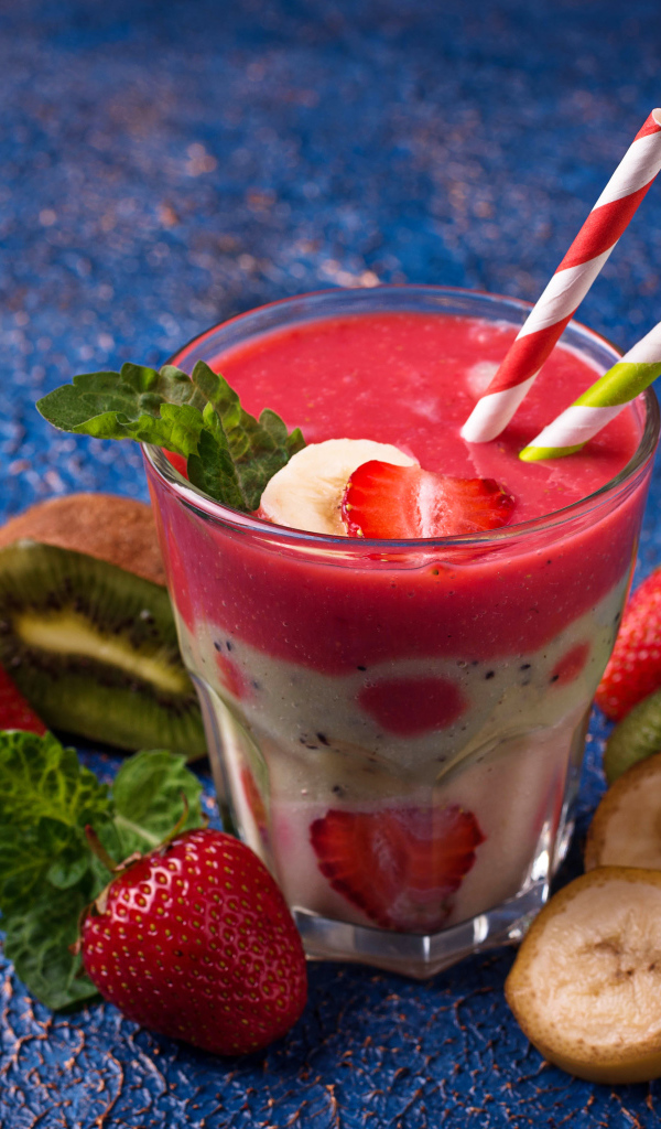 Фруктовый коктейль с клубникой, бананом и киви в стакане с трубочками