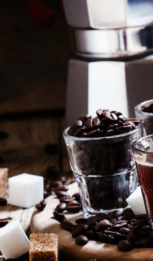 Стаканы с кофе, кофейными зернами и перемолотым кофе на столе с кубиками сахара