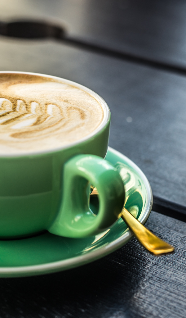 Зеленая чашка капучино с белой пенкой 